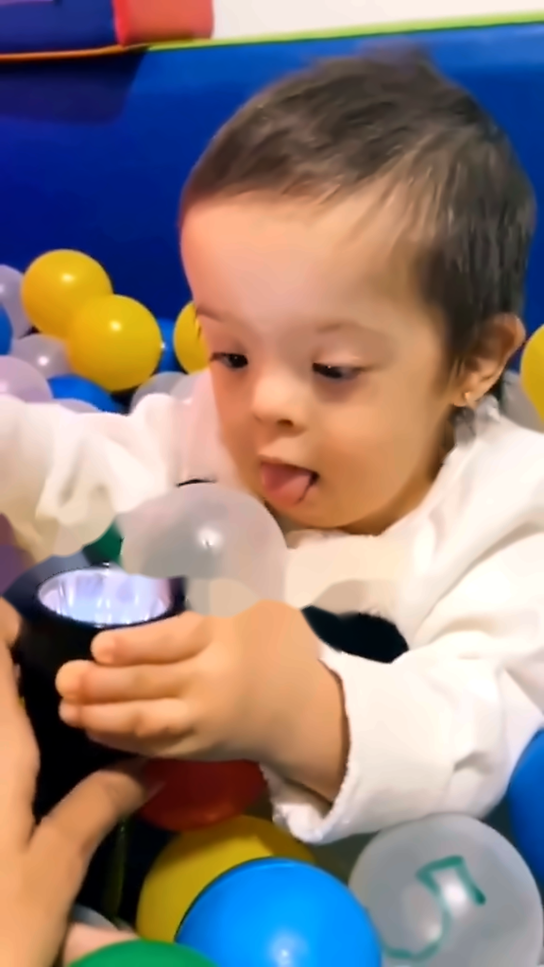 A Rafinha sorrindo enquanto brinca em uma piscina de bolinhas